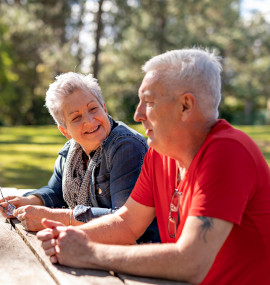 Middle aged couple sitting outside on a bench.